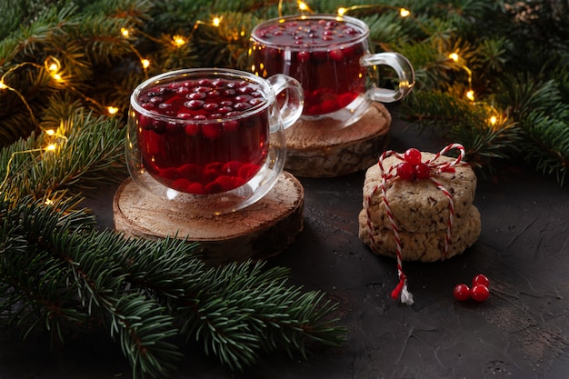 Zwei Tassen mit scharfem Weihnachtsgetränk mit Preiselbeeren und Kuchen. Weihnachts-Konzept