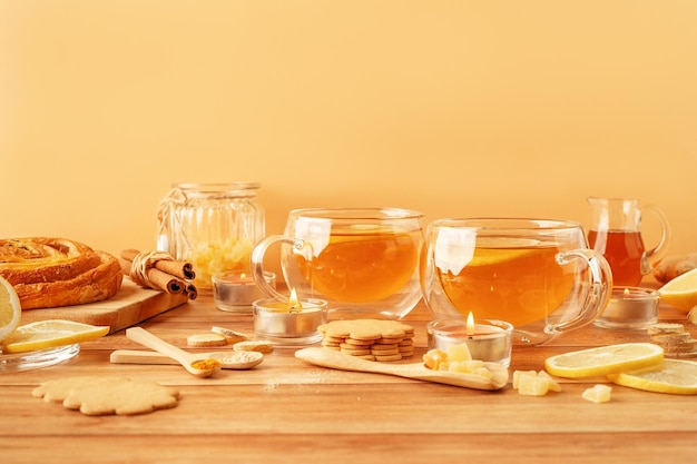 Zwei Tassen Tee mit Zutaten aus Zitronenhonig, Ingwerwurzel und Ingwerkeksen auf einem Holztisch. Naturheilkunde-Konzept-Attrappe für Ihr Design