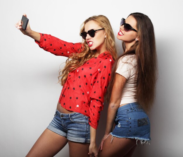 Zwei Teenager-Freundinnen in Hipster-Outfit machen Selfie an einem Telefon