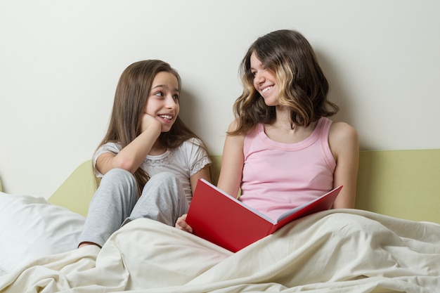 Zwei Teenager im Schlafanzug sitzen zu Hause im Bett