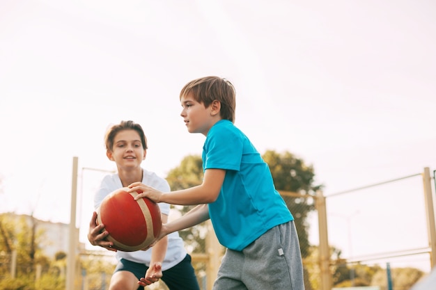 Zwei Teenager spielen Basketball auf dem Spielplatz. Die Athleten kämpfen im Spiel um den Ball