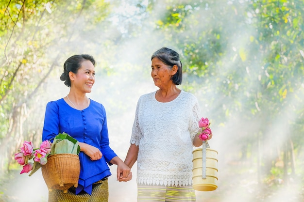 Zwei thailändische frauen und zwei menschen falteten rosa lotos, um heute morgen in den tempel zu gehen.