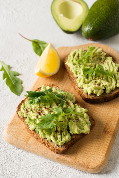 Zwei Toasts mit Avocado und grünem Salat zum Frühstück auf weißem Hintergrund