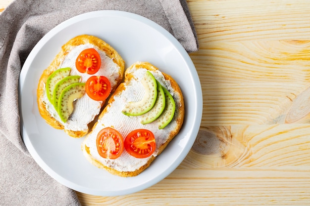 Zwei Toasts mit Avocado und Kirschtomaten auf Holzuntergrund