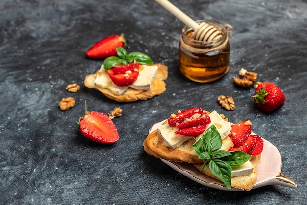 Zwei Toasts oder Bruschetta mit Erdbeeren, Käse, Camembert, Nüssen und Honig Sommerfrühstück Gesundes, sauberes Essen Vegane oder glutenfreie Ernährung