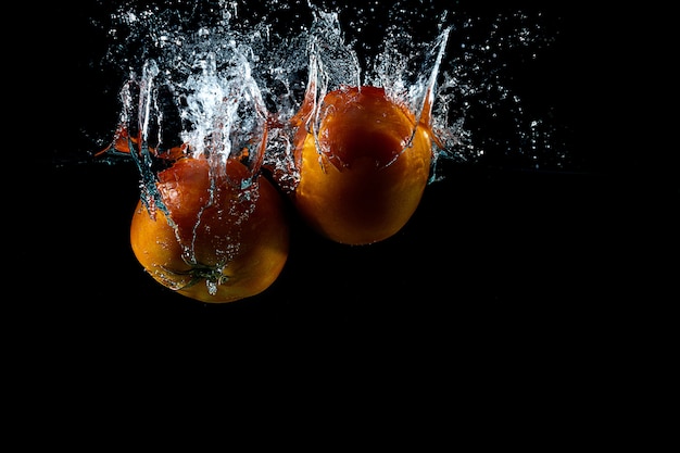 Zwei Tomaten spritzen auf Wasser