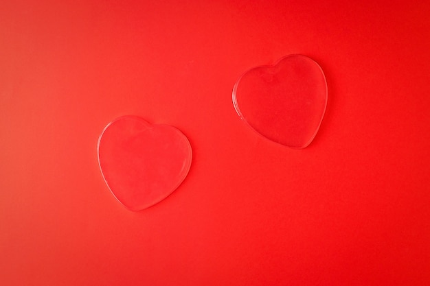 Zwei transparente Herzen auf einem leuchtend roten Hintergrund. Ein Symbol für Liebe und Leben.