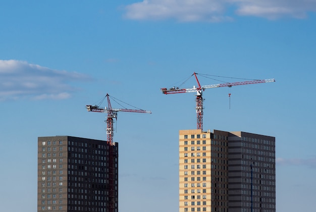 Zwei Turmdrehkrane auf dem Hintergrund von zwei im Bau befindlichen Häusern