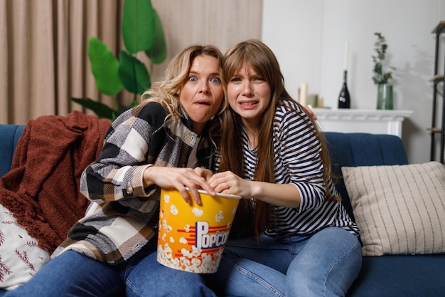 Zwei überraschte Frauen, die zu Hause etwas im Fernsehen ansehen