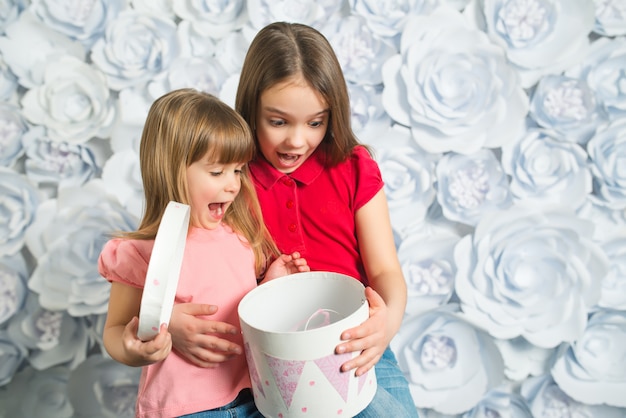 Zwei überraschte kleine Mädchen öffnen ein Geschenk