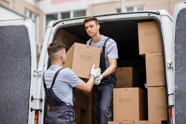 Foto zwei umzugshelfer in uniform entladen den transporter voller kisten haus umzugsdienst