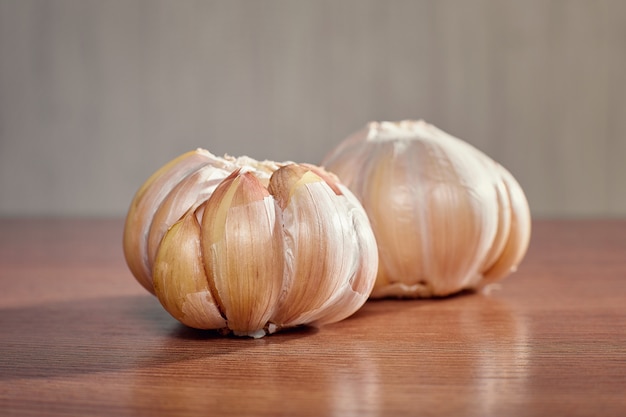 Zwei ungeschälte reife Knoblauchzehen nah oben liegen auf einem Holztisch