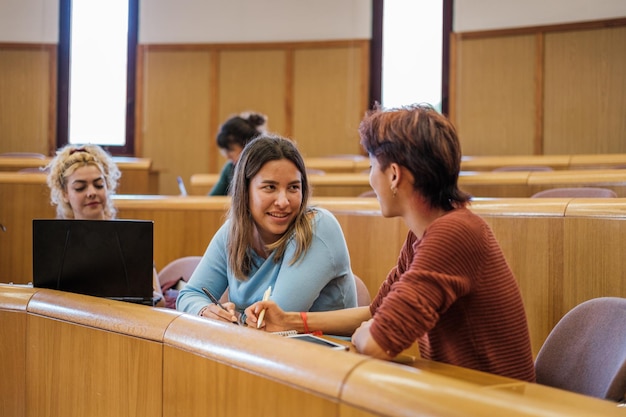 Zwei Universitätsstudenten unterhalten sich im Klassenzimmer, während sie auf den Lehrer warten Concept Studies Education Training