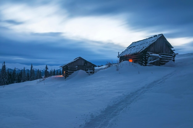 Zwei verlassene Holzhütten in den Winterbergen bei Sonnenuntergang