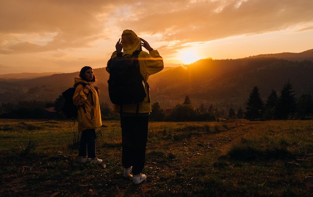 Zwei Wanderer stehen auf einer Wiese in den Bergen im Regen vor Sonnenuntergang