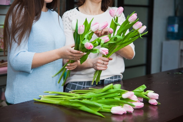 Zwei weibliche Floristendesigner, die Feiertags-Tulpensträuße am Blumenladen machen. Blumendekoration