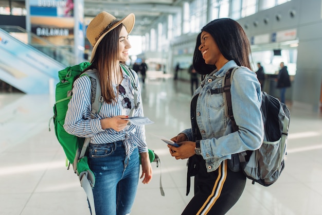 Zwei weibliche Touristen mit Rucksäcken im Flughafen