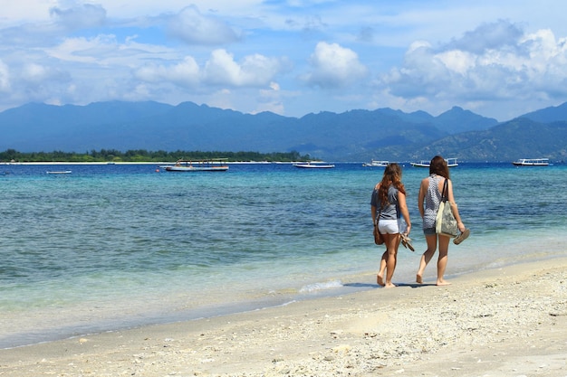 Zwei weibliche Touristen zu Fuß am Strand von Gili Trawangan, Indonesien.