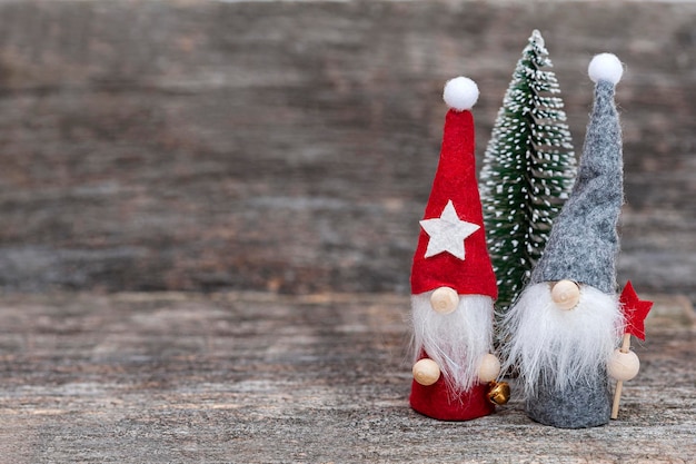 Zwei Weihnachtszwerge und ein Weihnachtsbaum auf einem hölzernen Hintergrund Textfreiraum