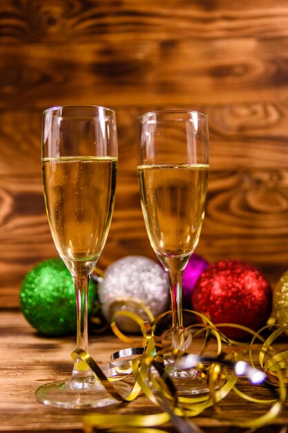 Zwei Weingläser mit Champagner und verschiedenen Weihnachtsdekorationen auf rustikalem Holztisch