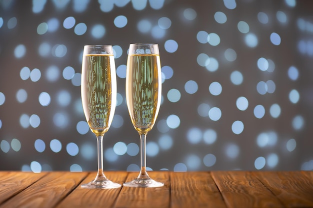 Zwei Weingläser mit sprudelndem Champagner auf verschwommenem funkelnden Lichthintergrund