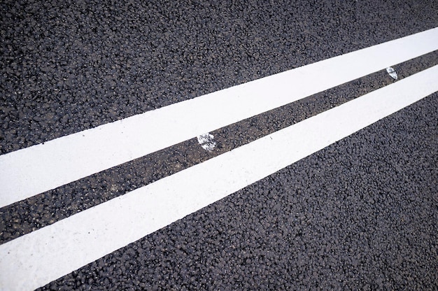 Foto zwei weiße durchgezogene linien auf einer neuen asphaltstraße. nahansicht.