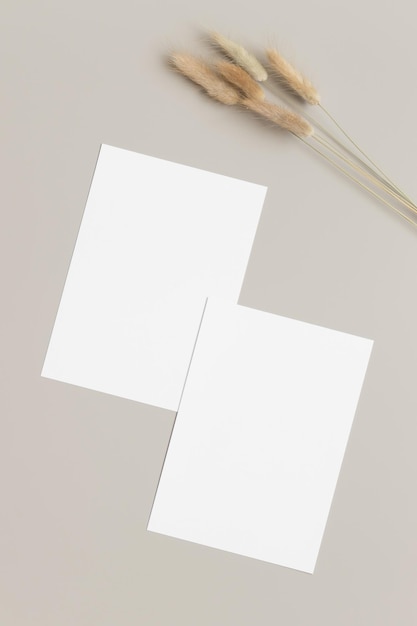Foto zwei weiße einladungskarten mit lagurus-dekoration auf einem beigen tisch im verhältnis 5 x 7 ähnlich a6 a5