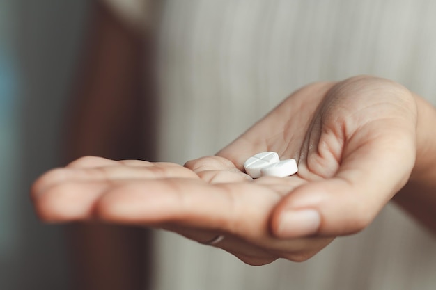 Foto zwei weiße pillen auf der hand einer asiatischen frau für medizinisches und gesundheitliches konzept