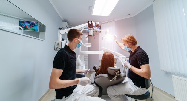 Zwei Zahnärzte untersuchen die Zähne des Patienten für die weitere Behandlung.