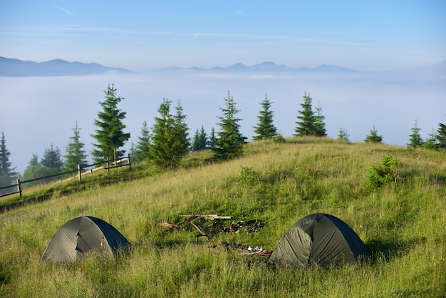 Zwei Zelte im Wanderlager in den Bergen am sonnigen Morgen mit Blick auf unglaublichen Nebel aus einem Tal