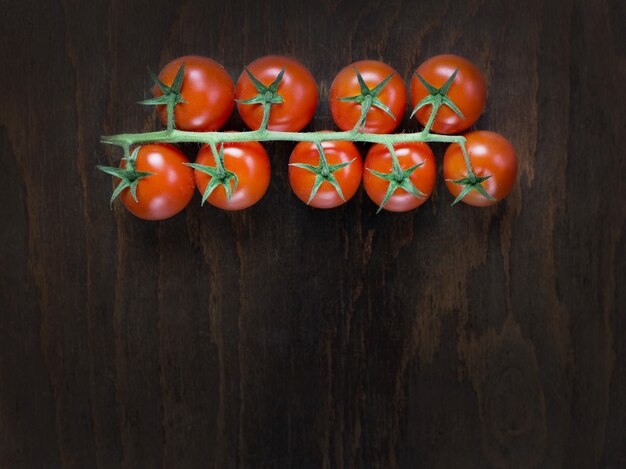 Zweig der roten reifen frischen Kirschtomaten auf einem Holzbrett