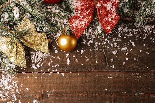 Zweige eines Weihnachtsbaumes und Weihnachtsschmuck im Schnee auf Holzbrett