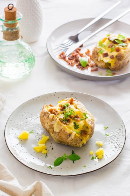 Zweimal gebackene Kartoffeln in ihren Schalen mit Käse- und Speckkrümeln auf Tellern auf einem Holztisch Flexitarian Diet Vertical vew