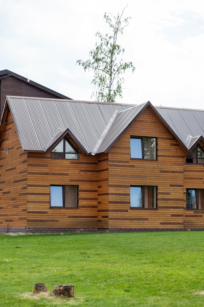 Zweistöckiges Holzhaus mit Fenstern Natur mit grünem Rasen. Verkauf oder Kauf von neuen Häusern.