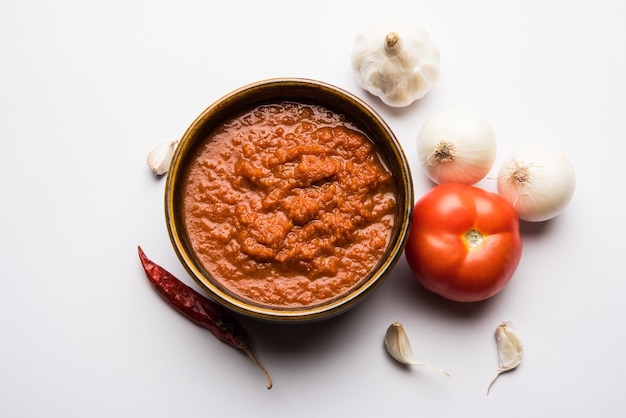 Zwiebel-Tomaten-Masala oder Püree für indische Soße, serviert in einer Schüssel mit rohem Tamatar, Pays und Lehsun und rotem Chili,