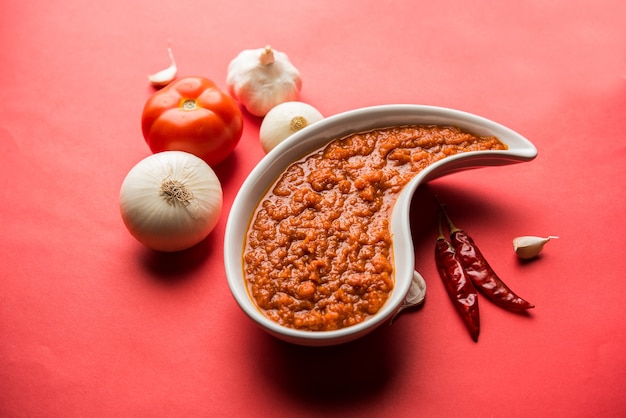 Zwiebel-Tomaten-Masala oder Püree für indische Soße, serviert in einer Schüssel mit rohem Tamatar, Pays und Lehsun und rotem Chili,