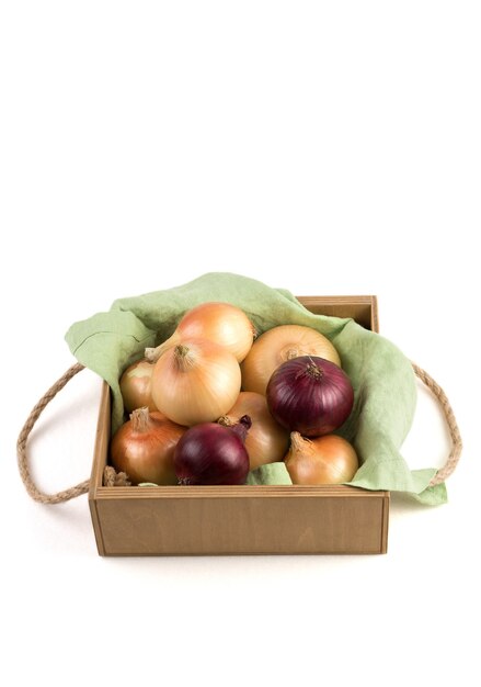 Zwiebeln verschiedener Sorten in einer schönen hölzernen Verpackungsbox auf einer Leinenserviette, isoliert.