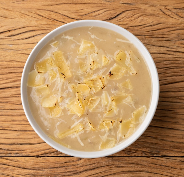 Zwiebelsuppe mit Käse in einer Schüssel über Holztisch