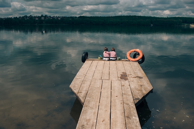 Zwillingsschwestern auf hölzernem Pier