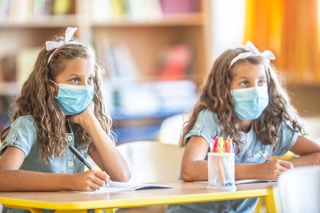 Zwillingsschwestern mit Gesichtsmaske zurück in der Schule während der COVID-19-Quarantäne.