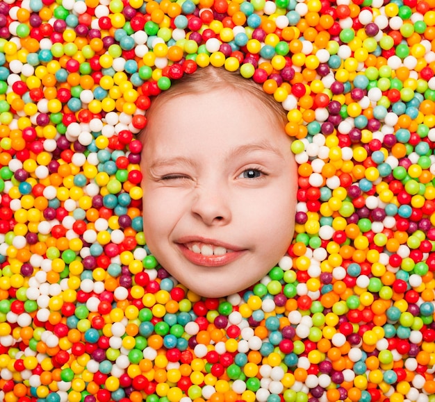 Zwinkerndes Kind, das in Süßigkeiten posiert