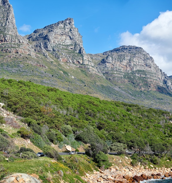 Zwölf Apostel auf dem Tafelberg in Kapstadt vor einem bewölkten blauen Himmelshintergrund Szenische Landschaftsansicht von üppigen grünen Pflanzen und Bäumen, die um ein majestätisches felsiges Tal wachsen, um die Natur zu erkunden