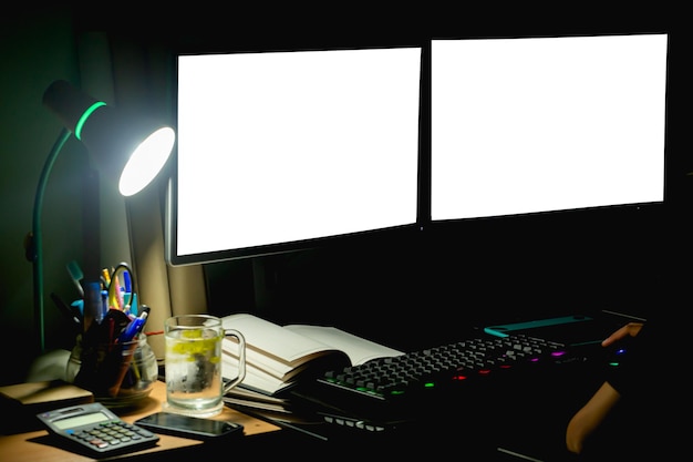 2 computer monitors on the desk at night