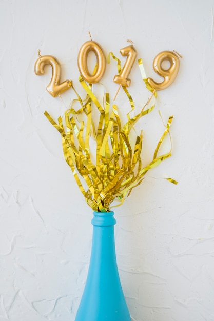 Free photo 2019 inscription from candles with tinsel and bottle