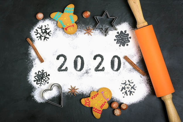 2020 text made with flour with decorations on black . flat lay.