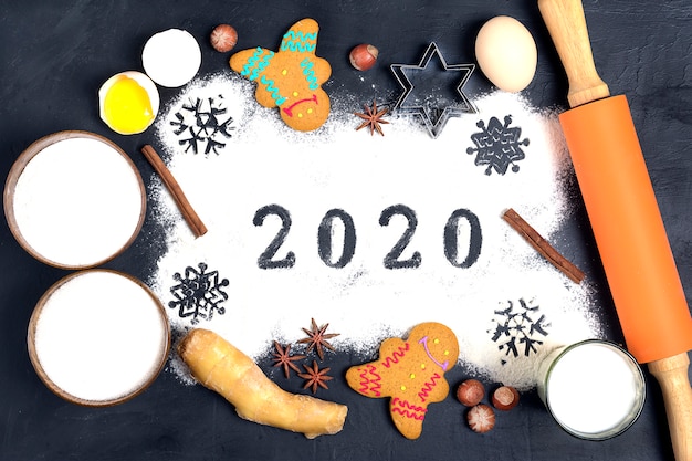 2020 text made with flour with decorations on black . flat lay.