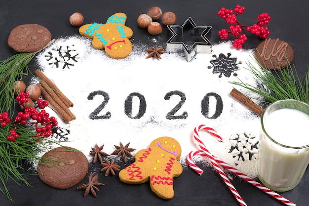 2020 text made with flour with decorations on black . flat lay.