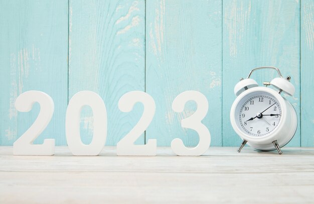 '2023' made with plastic numbers and an alarm clock on a blue wooden