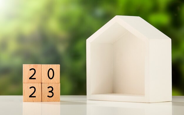 '2023' written on wooden cubes and a box house on a table