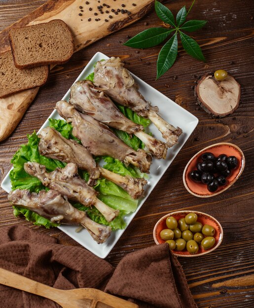 6 pieces of boiled turkey legs served with black and green olives, bread